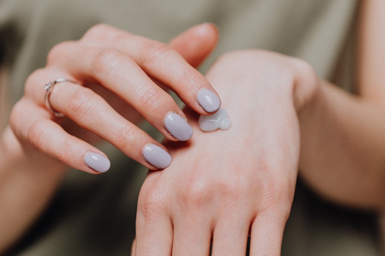 Crafting Captivating Headlines: Your awesome post title goes here A woman's hand applying moisturizing cream, emphasizing skincare and nail beauty.