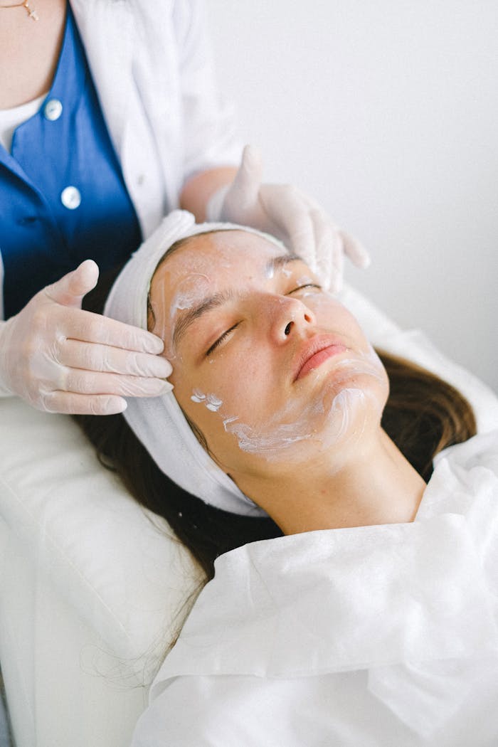 services-04 Woman receiving a facial treatment at a spa, promoting skin health and relaxation.